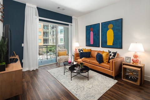 a living room with a brown couch and two paintings on the wall